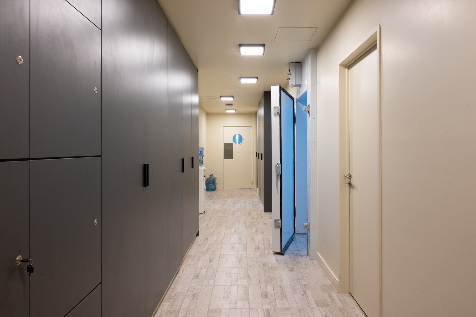 Corredor longo com armários embutidos e divisória azul — projeto KALYS PIZZA, por AB ARQUITECTURA, em Núñez