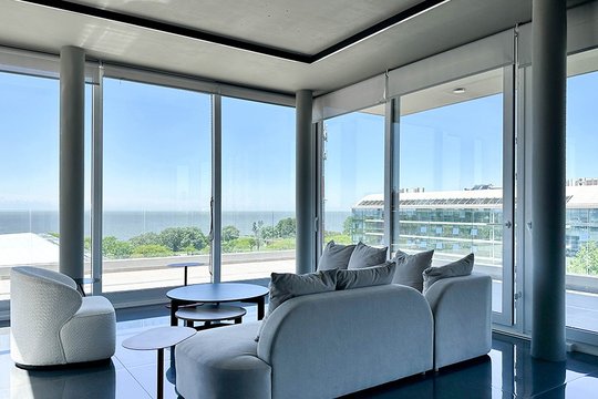 Living moderno con vista al mar y ventanales — proyecto Libertador Blvd, por MUCHTEK, en Vicente López