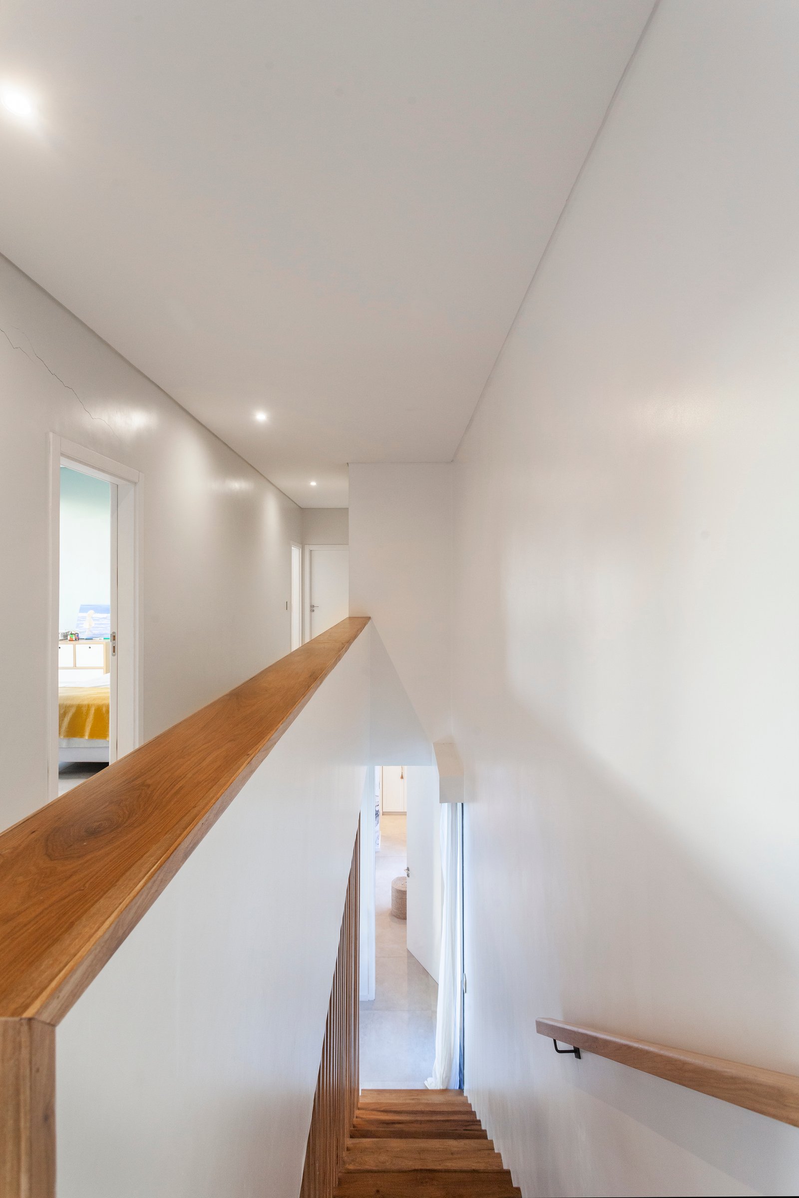 Pasillo y escalera moderna de madera y paredes blancas — proyecto CASA HS143, por A'PRIMA - Arquitectura Sustentable, en km 7.5 Ruta 25