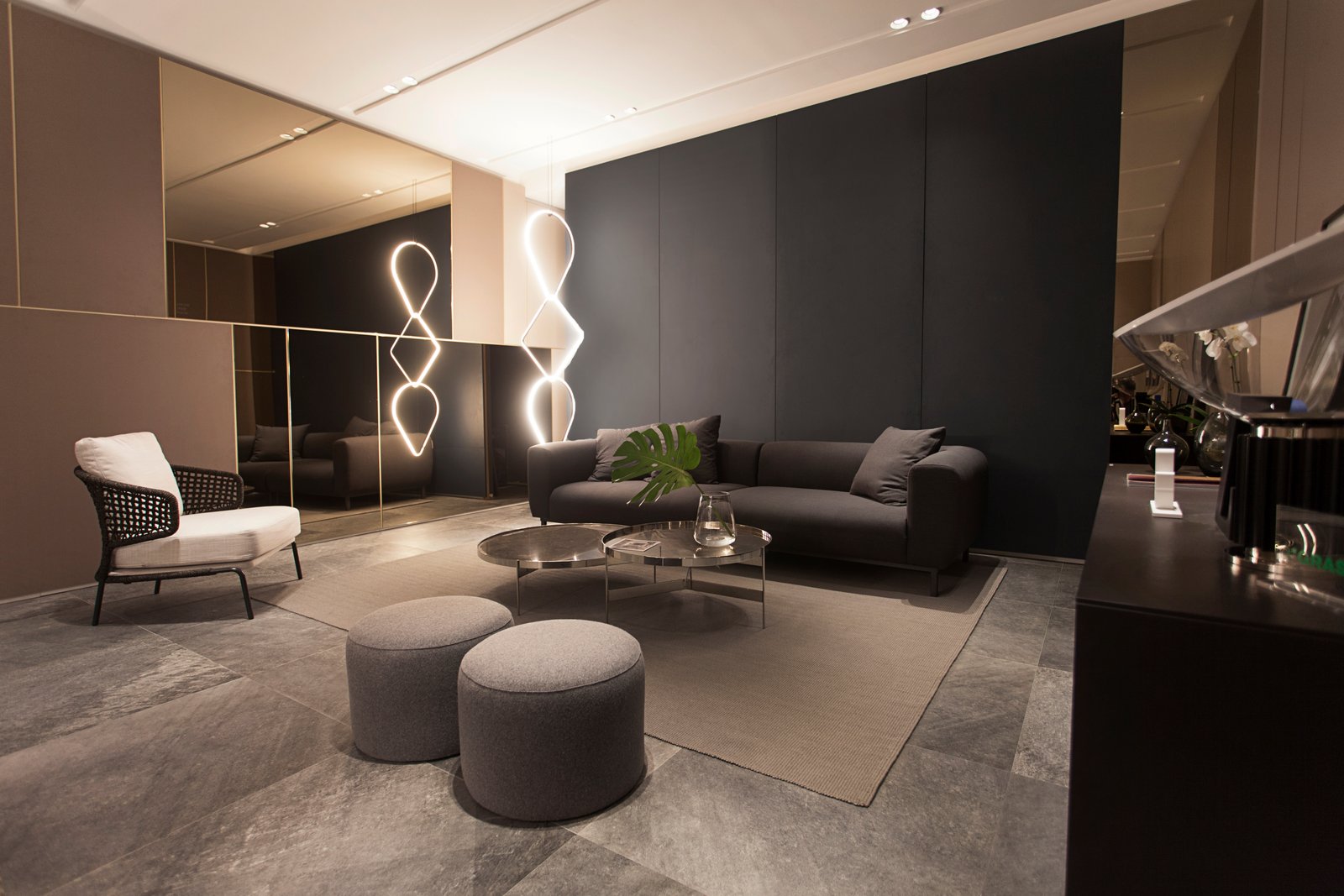 Sala de estar moderna com sofá curvo bege e parede escura — projeto Piedras, por Vite Porcellanato