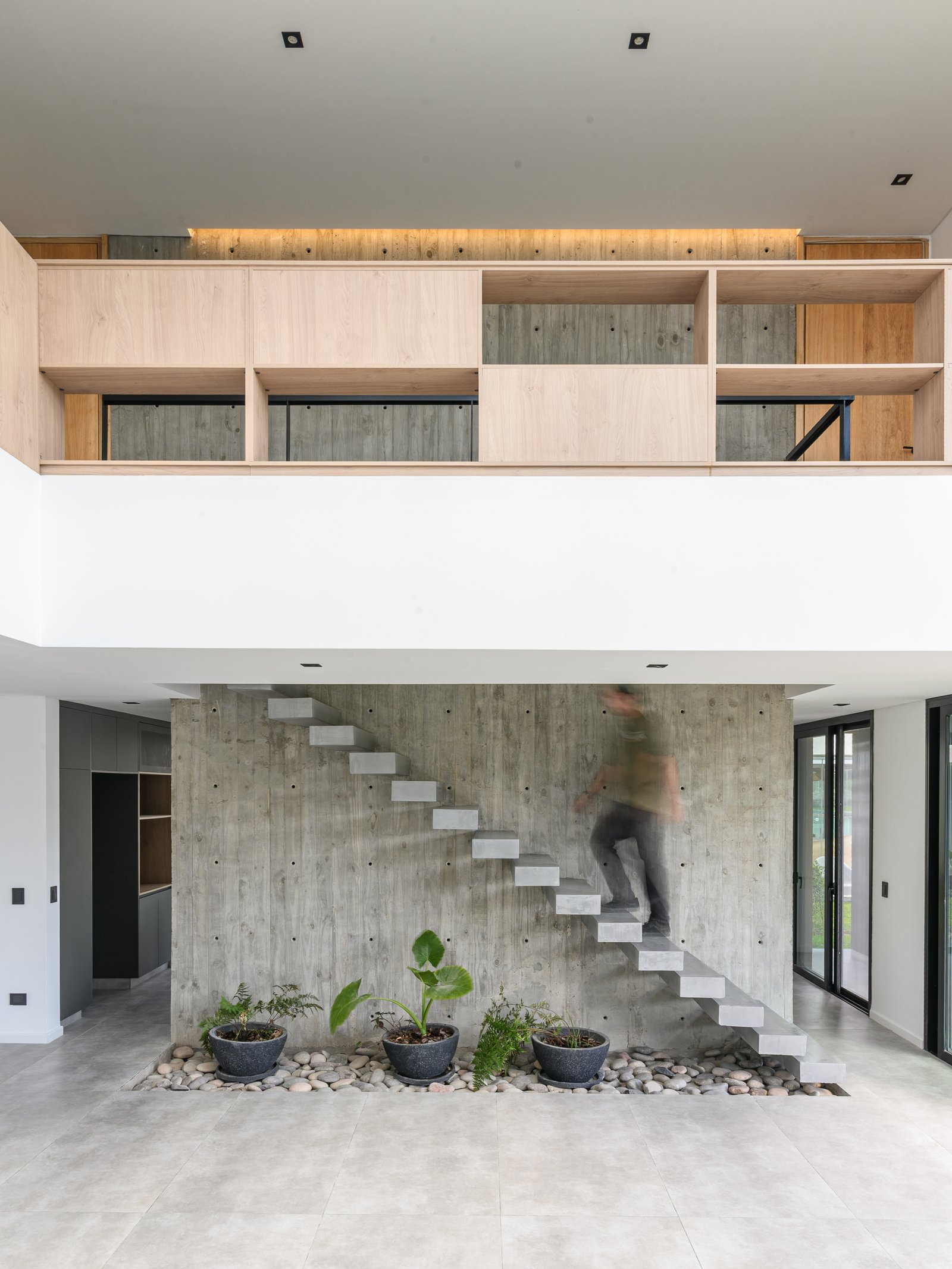 Escada flutuante de concreto em interior moderno com painéis de madeira — projeto CASA CONCRETO, por Auge desarrollos & crowdfunding, em Nordelta
