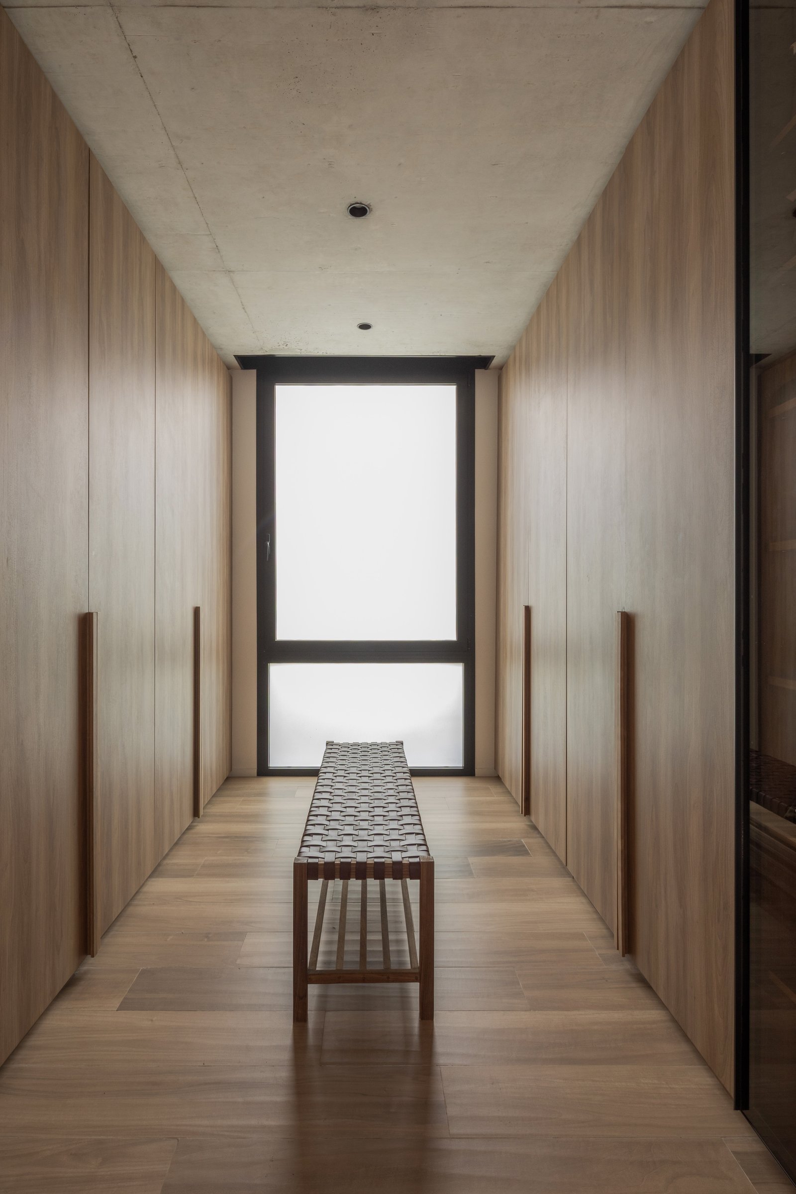 Pasillo minimalista con revestimiento de madera y gran ventana — proyecto Casa PLANALTO, por Grupo CRBN, en Av. Pres. Perón 10298