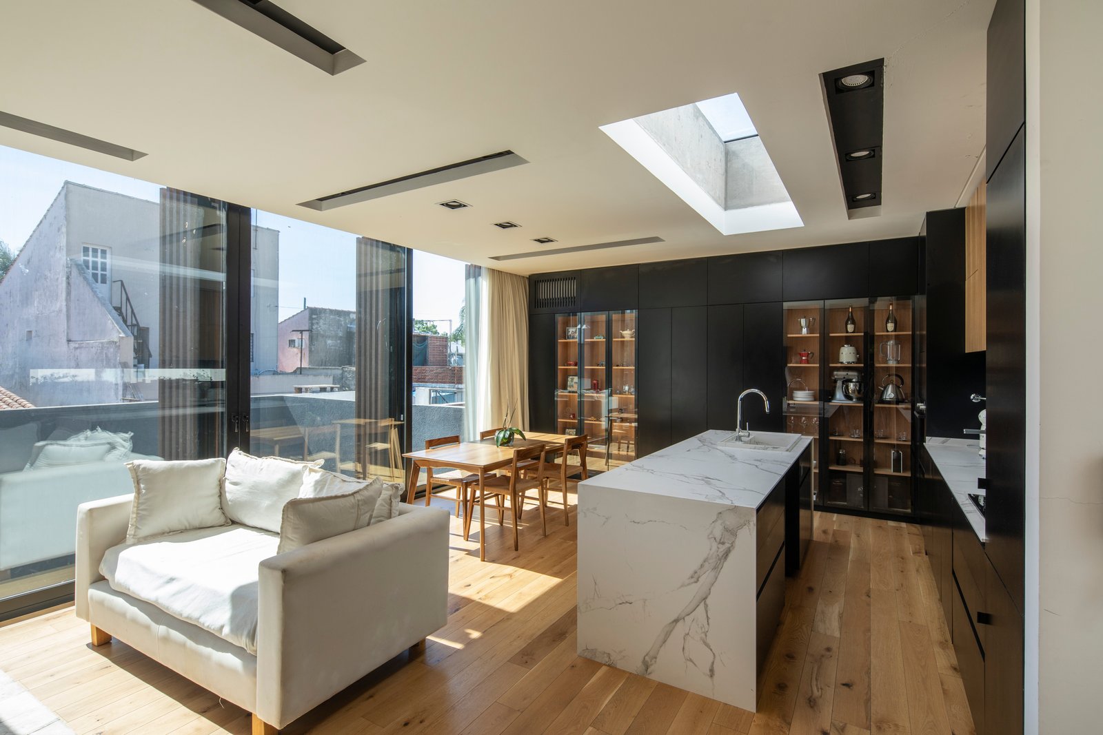 Living moderno integrado con isla de cocina y mucha luz natural — proyecto Casa MECHA, por Grupo CRBN, en B1712 Castelar
