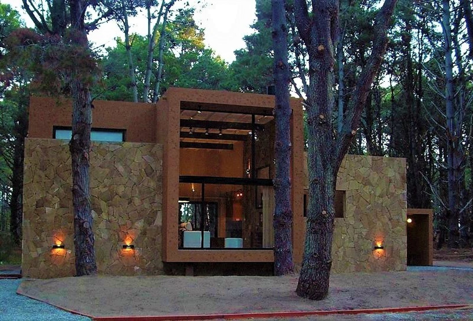 Fachada moderna na floresta com pedra e madeira — projeto LA  ALHAMBRA, por GJF estudio, em Costa del Este