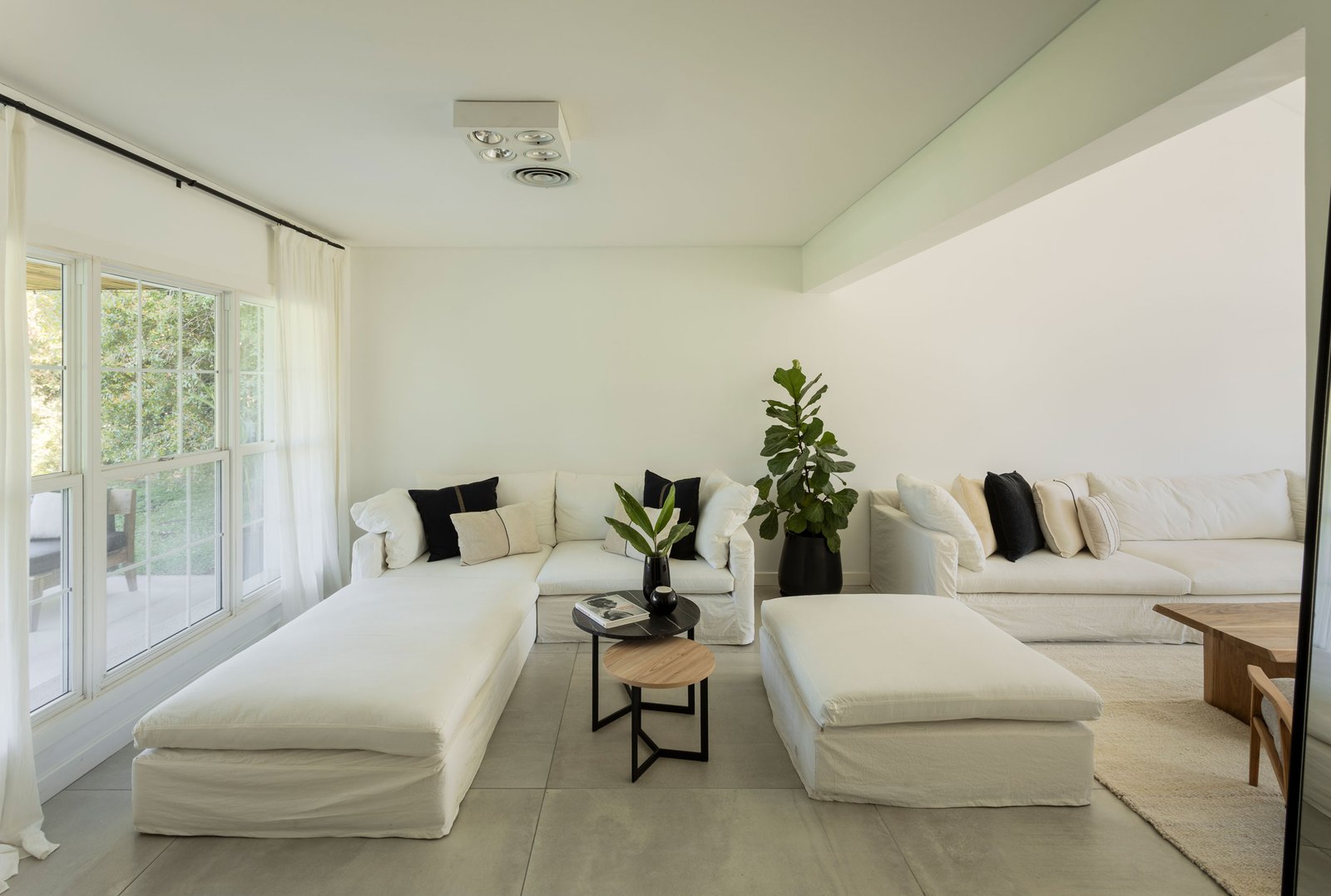 Living moderno con sofás modulares blancos y grandes ventanales — proyecto REFORMA GDLT, por Rastro Estudio, en Nordelta