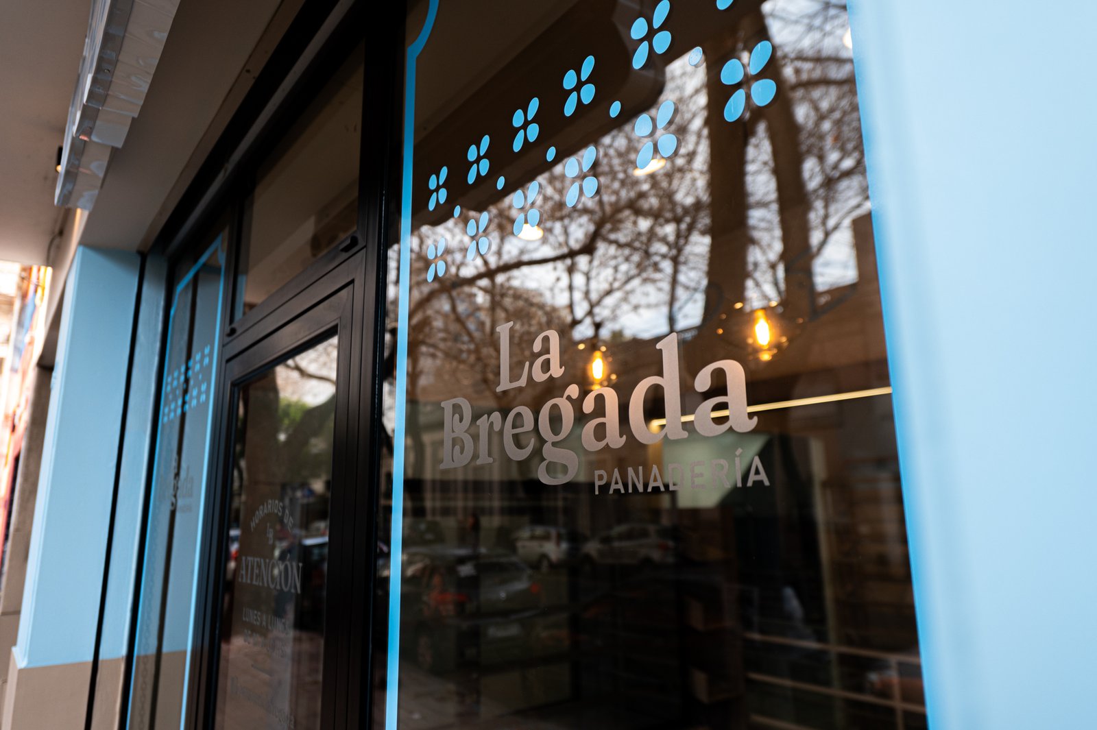 fachada de local comercial con vidrios de piso a techo — proyecto La Bregada Panadería , por Ailén Lucero Arquitectura, en La Plata
