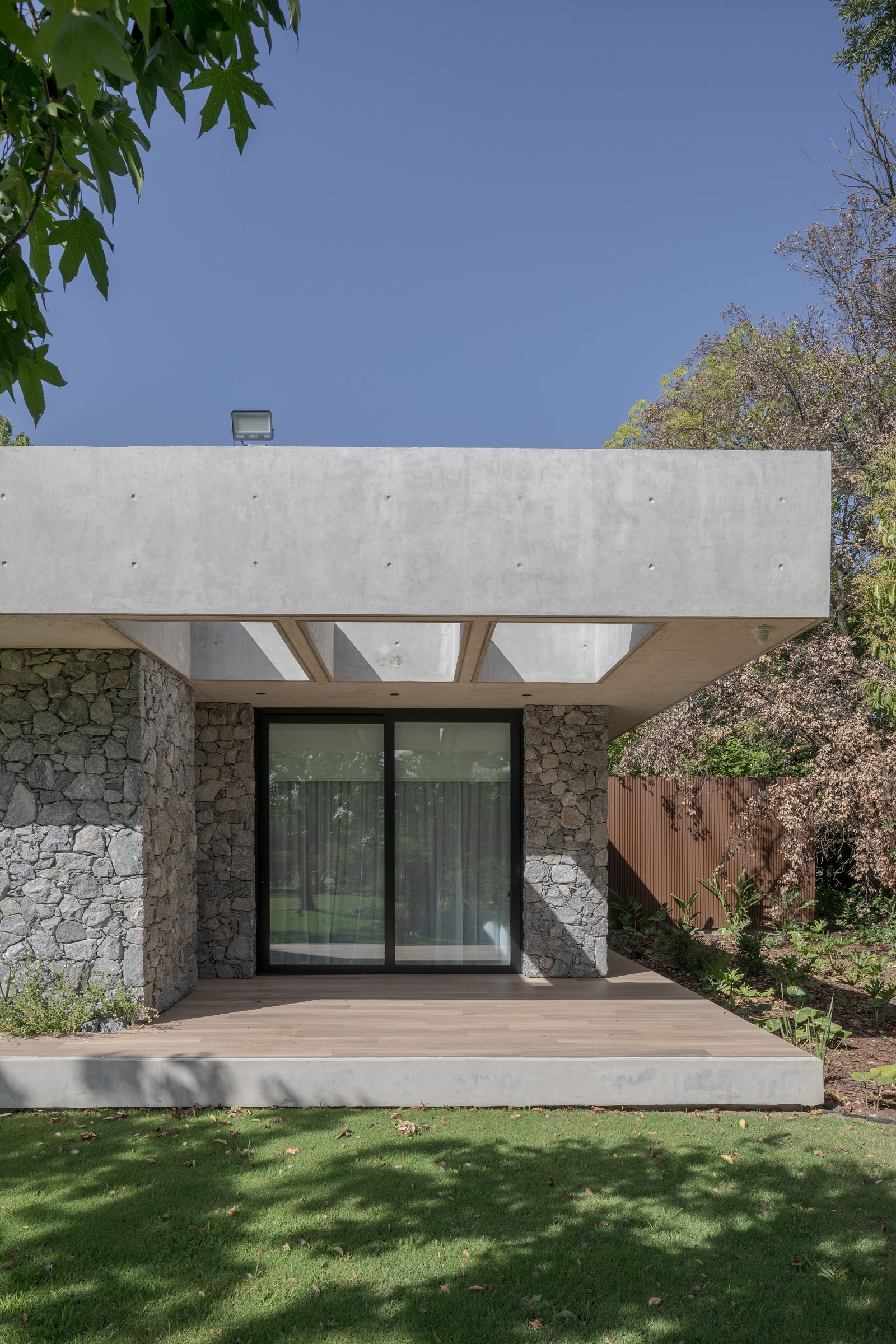 Fachada moderna con revestimiento de piedra y hormigón flotado — proyecto Casa PLANALTO, por Grupo CRBN, en Av. Pres. Perón 10298