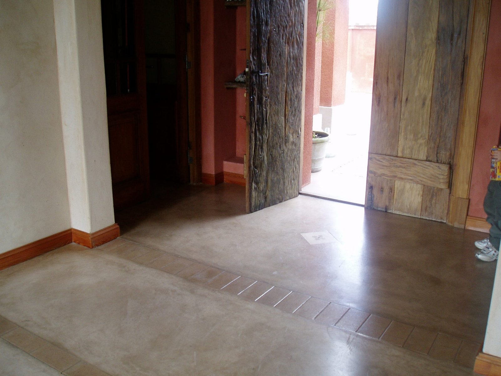 Entrada con puerta doble de madera rústica y suelo de hormigón pulido — proyecto Casas Santa Maria, por PROTEX, en B1648 Tigre