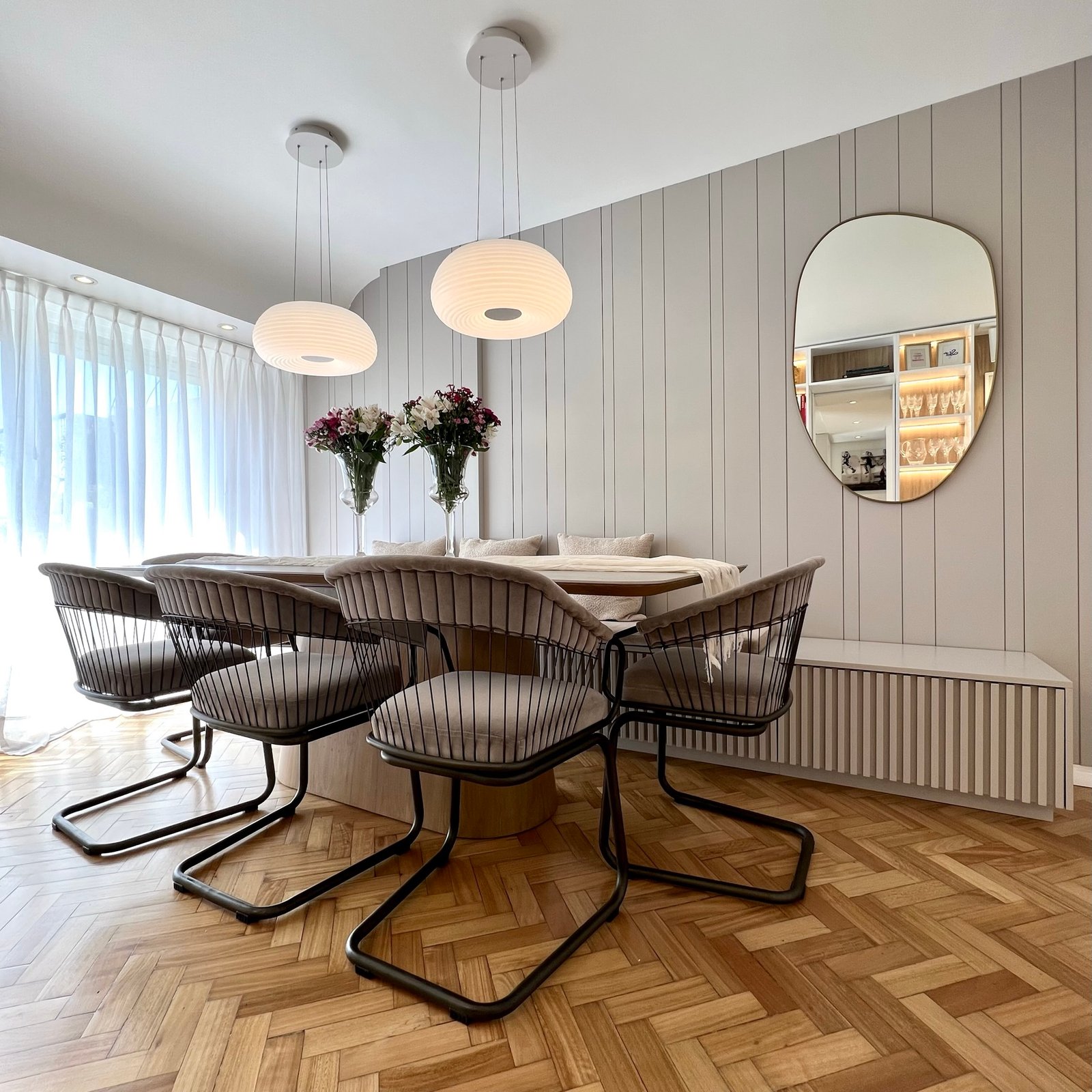 Sala de jantar moderna com mesa oval e cadeiras estofadas, detalhes em madeira — projeto Cramer I, por MDBK Arquitectura, em Belgrano