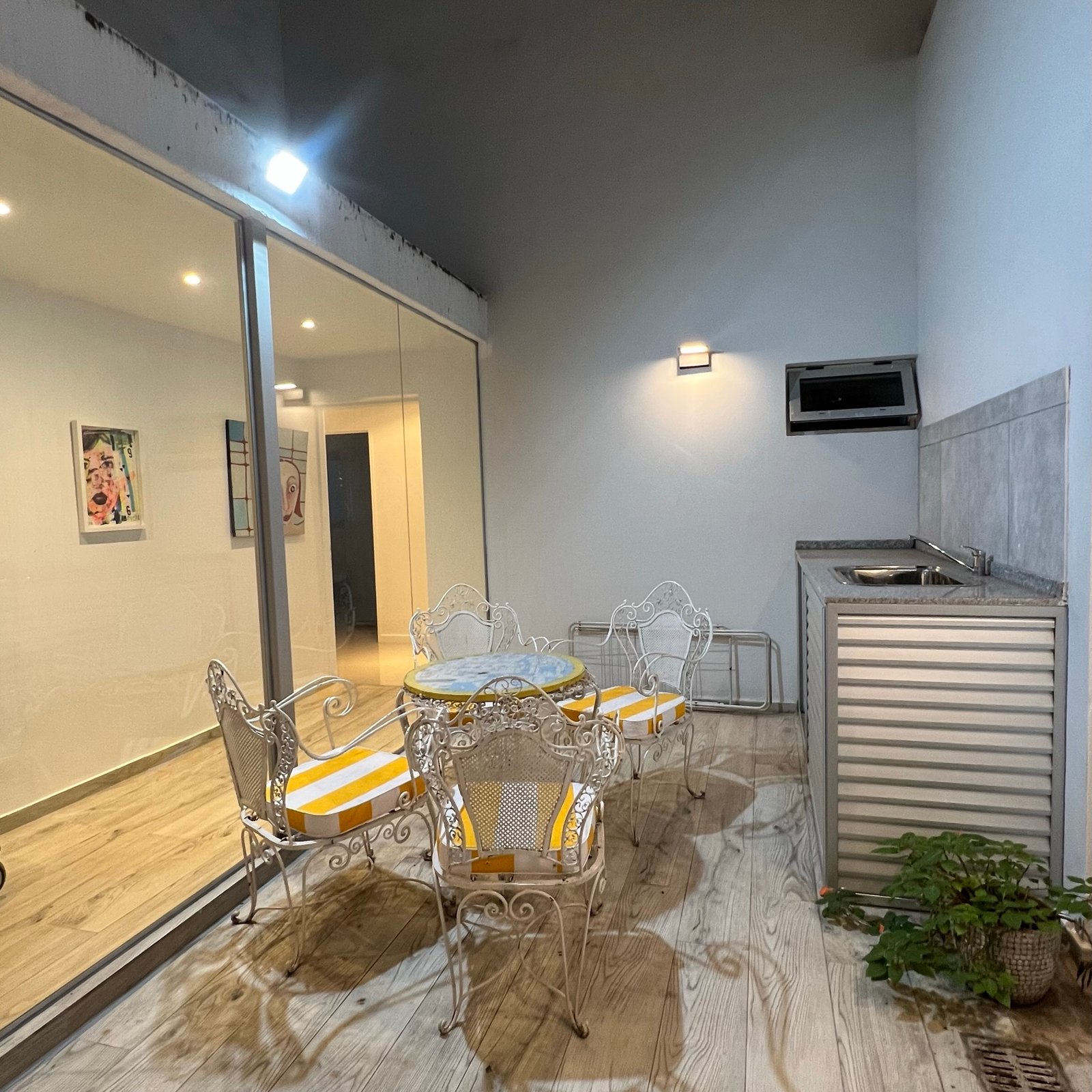 Patio mediterráneo con muebles de hierro forjado y piso de madera — proyecto Epuyen II, por MDBK Arquitectura, en Caballito