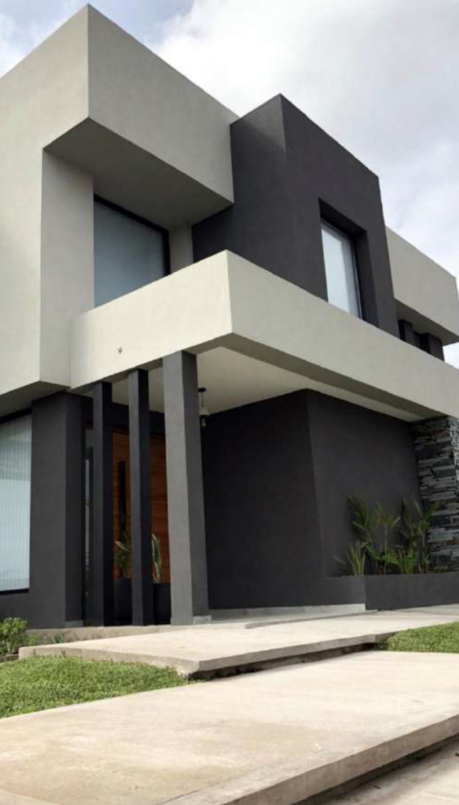Fachada de casa moderna com volumes geométricos em concreto cinza e preto — projeto Vivienda ACG, por MMCZ STUDIO, em Campo Grande