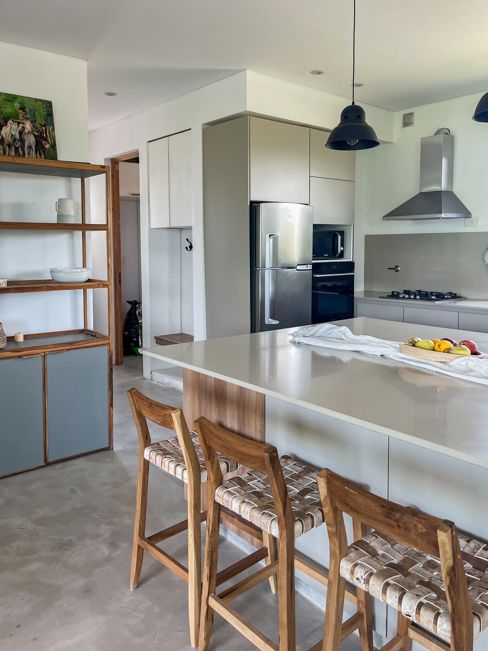 Cocina moderna con isla, taburetes de madera y suelo de cemento pulido — proyecto Casa San Fermin 200, por R+B arquitectos, en Pasteur 662