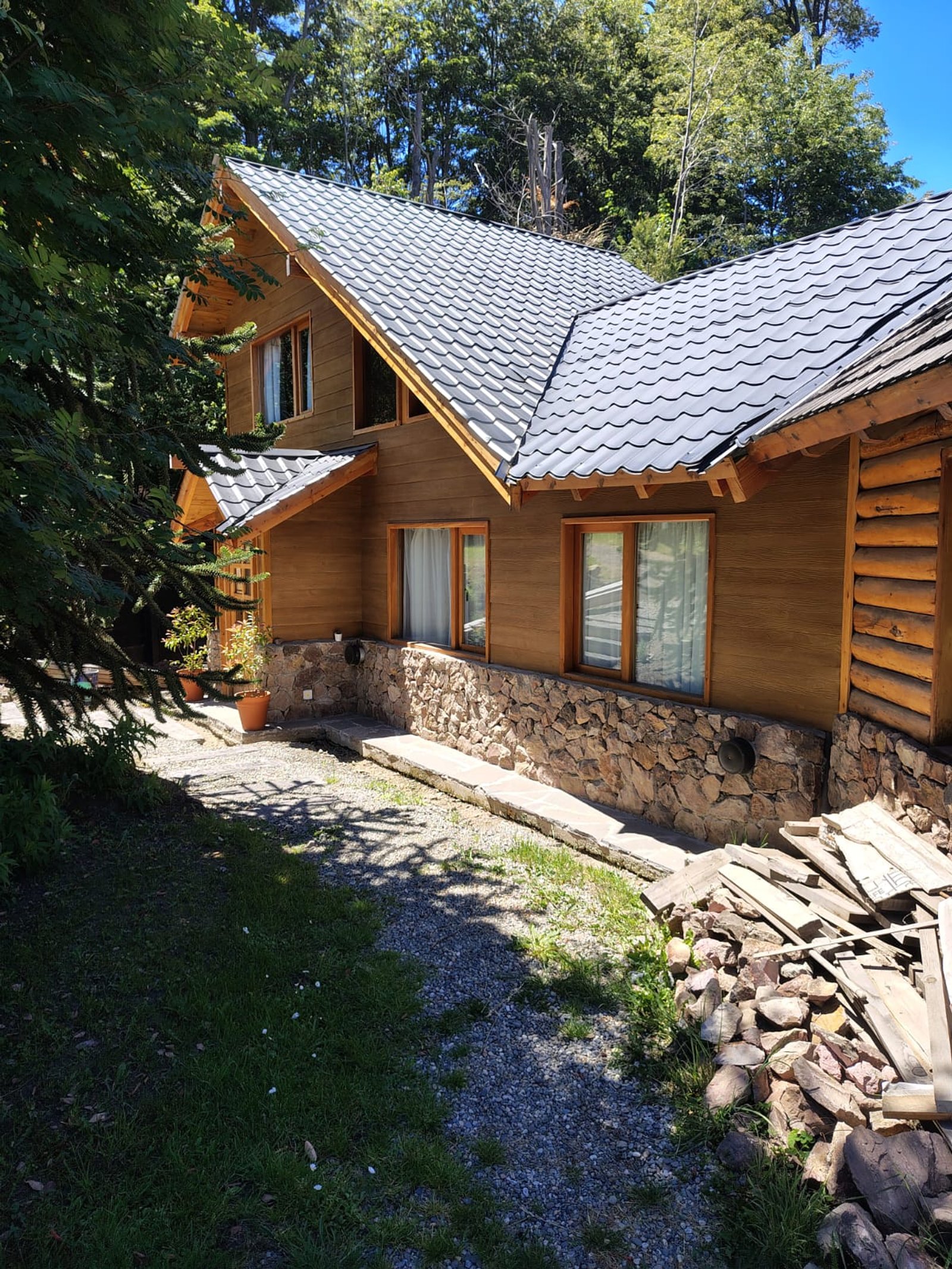 Casa rústica de madeira com base de pedra e telhado de metal — projeto Modelo Verona Plus, por Yrigoyen Construcciones, em Avellaneda