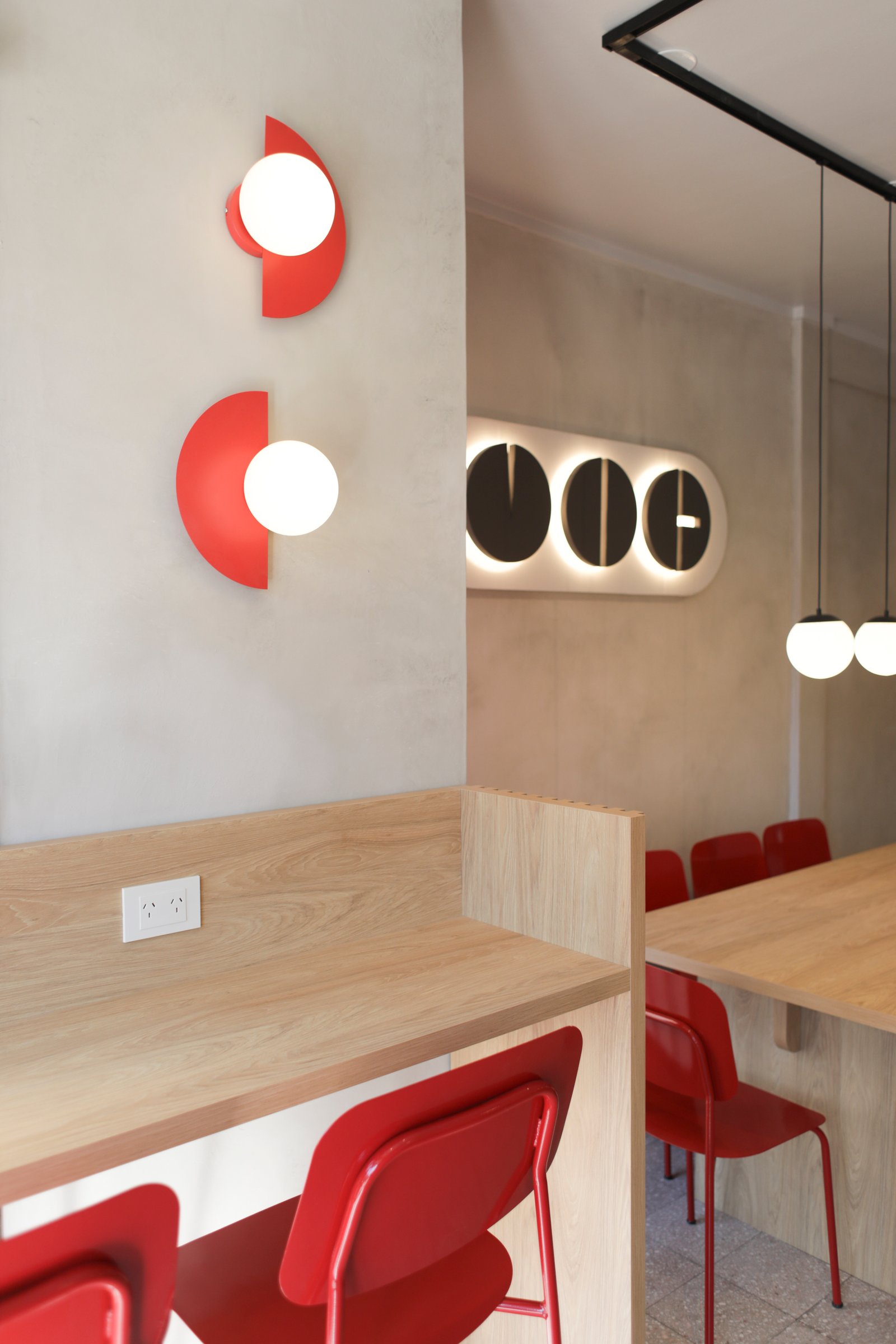 Interior comercial moderno con luces geométricas rojas y sillas rojas — proyecto Fonda Cafe, por Jeitinho Estudió Creativo, en La Plata