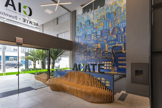 Entrada comercial moderna con asiento sculptórico y mural artístico azul — proyecto Hall Alcate Downtown, por Beatriz Zeglin Arq. Interiores