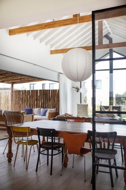 Comedor luminoso con mesas blancas, sillas variadas y techo de vigas madera — proyecto JI 103, por Estudio Diez Muzzio
