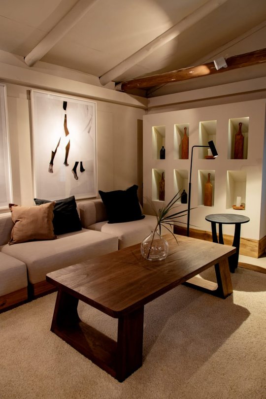 Living moderno con sofá beige, mueble bar iluminado y techo de vigas — proyecto PILARA, por ESTUDIOPET, en Pilará