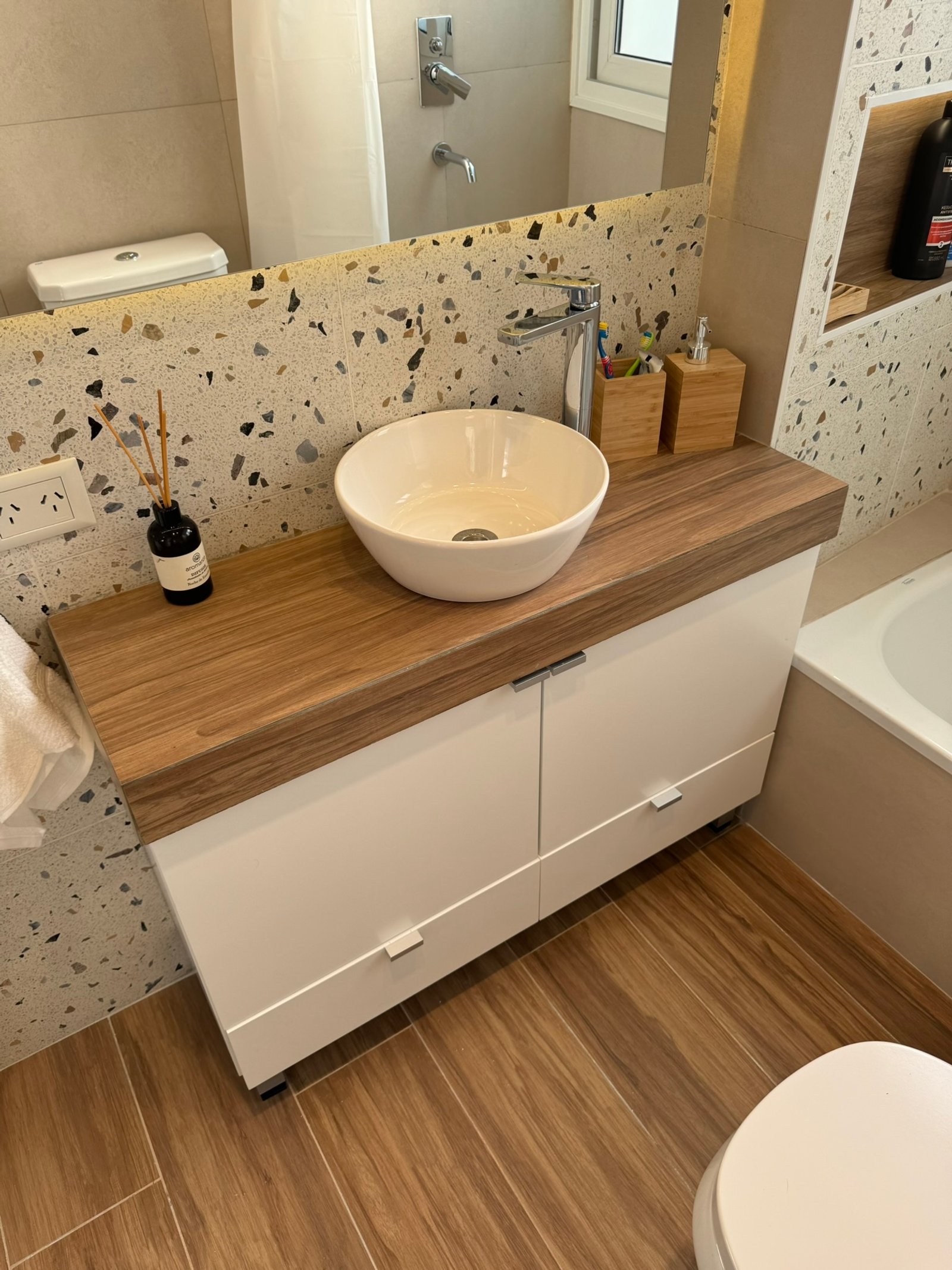 baño moderno con vanitory de madera, bacha redonda y pared de}$ terrazzo — proyecto Apolinario, por MDBK Arquitectura, en Villa Crespo