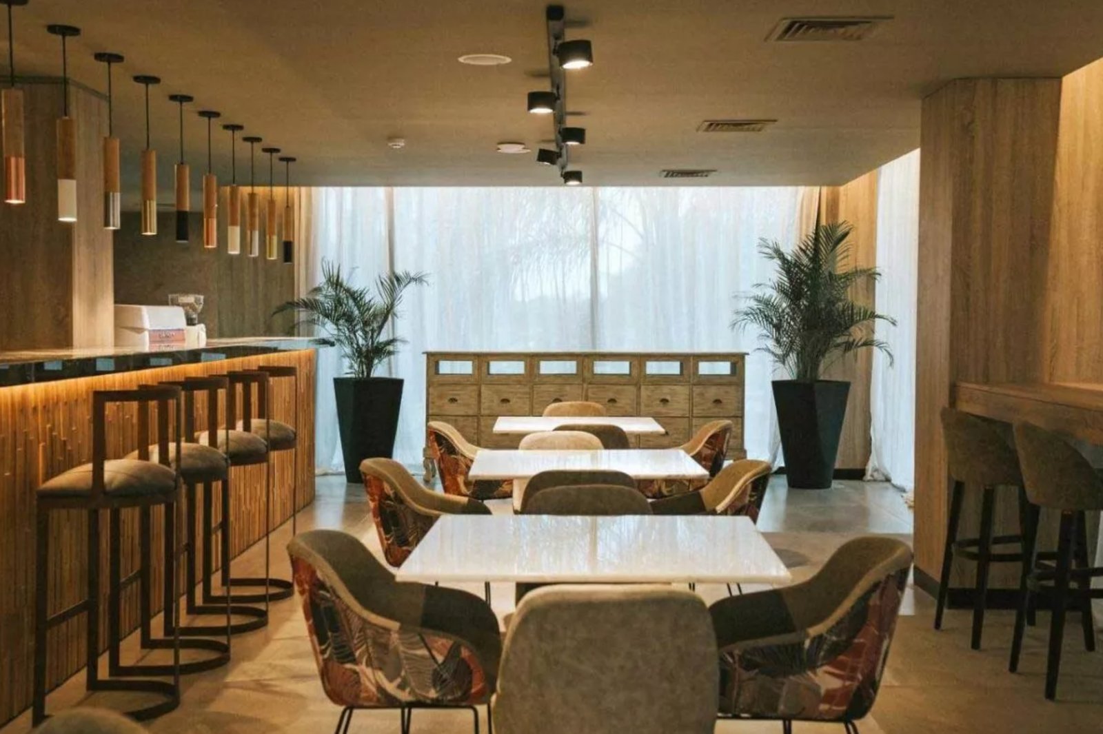Comedor de restaurante con sillas estampadas y revestimiento de madera — proyecto Distinción LED y Confort en Howard Johnson, por ATRIM GLOBAL, en Resistencia