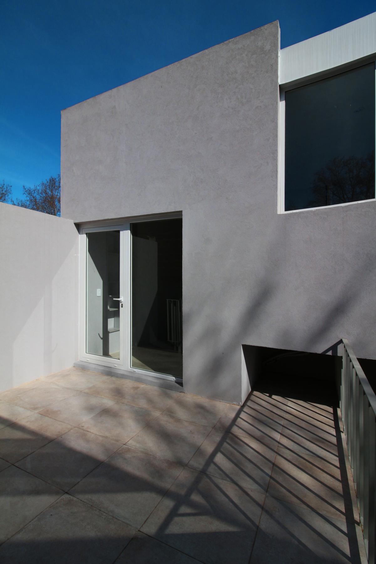 Fachada moderna com porta dupla de vidro e janela escura — projeto Tapalque 4455, por BARBALACO ARQUITECTOS, em Buenos Aires