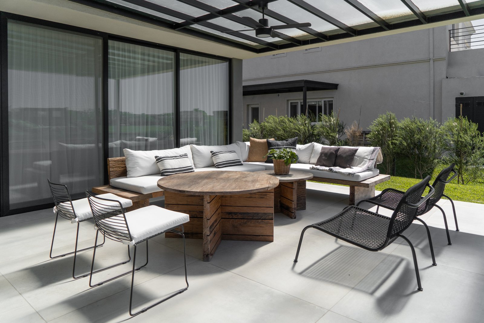 Living exterior moderno con techo vidriado y muebles grises — proyecto PROYECTO VISTAS, por July Acosta Home, en Belén de Escobar