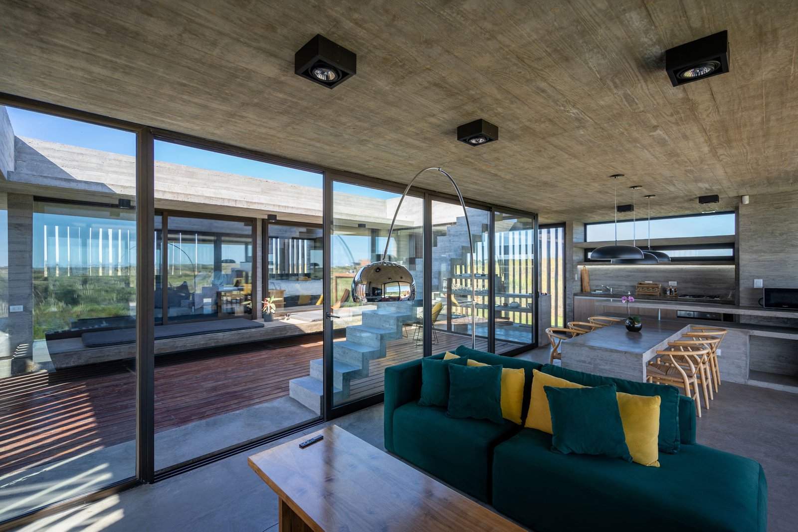 Sala de estar moderna com concreto aparente e vista para o mar — projeto Casa Médanos, por Besonías Almeida arquitectos, em JWRC+MQ