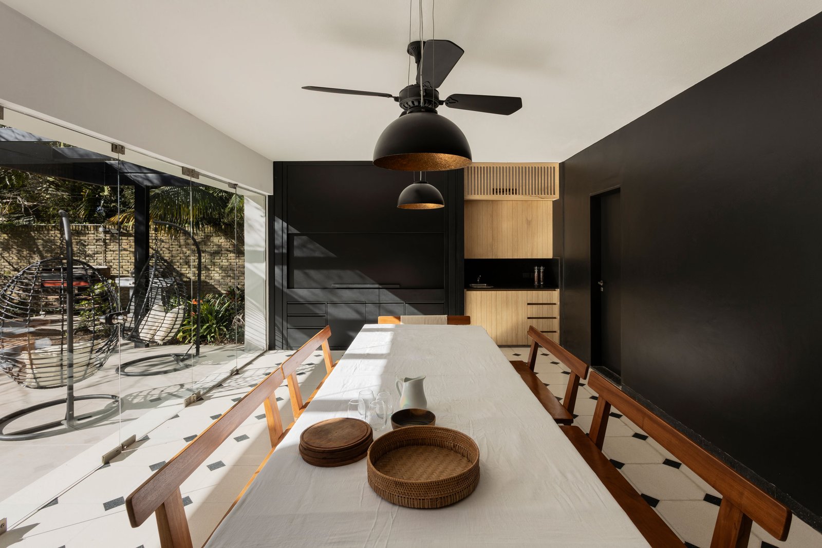 comedor moderno con pared negra y luz industrial — proyecto REFORMA DG, por Rastro Estudio, en Punta Chica