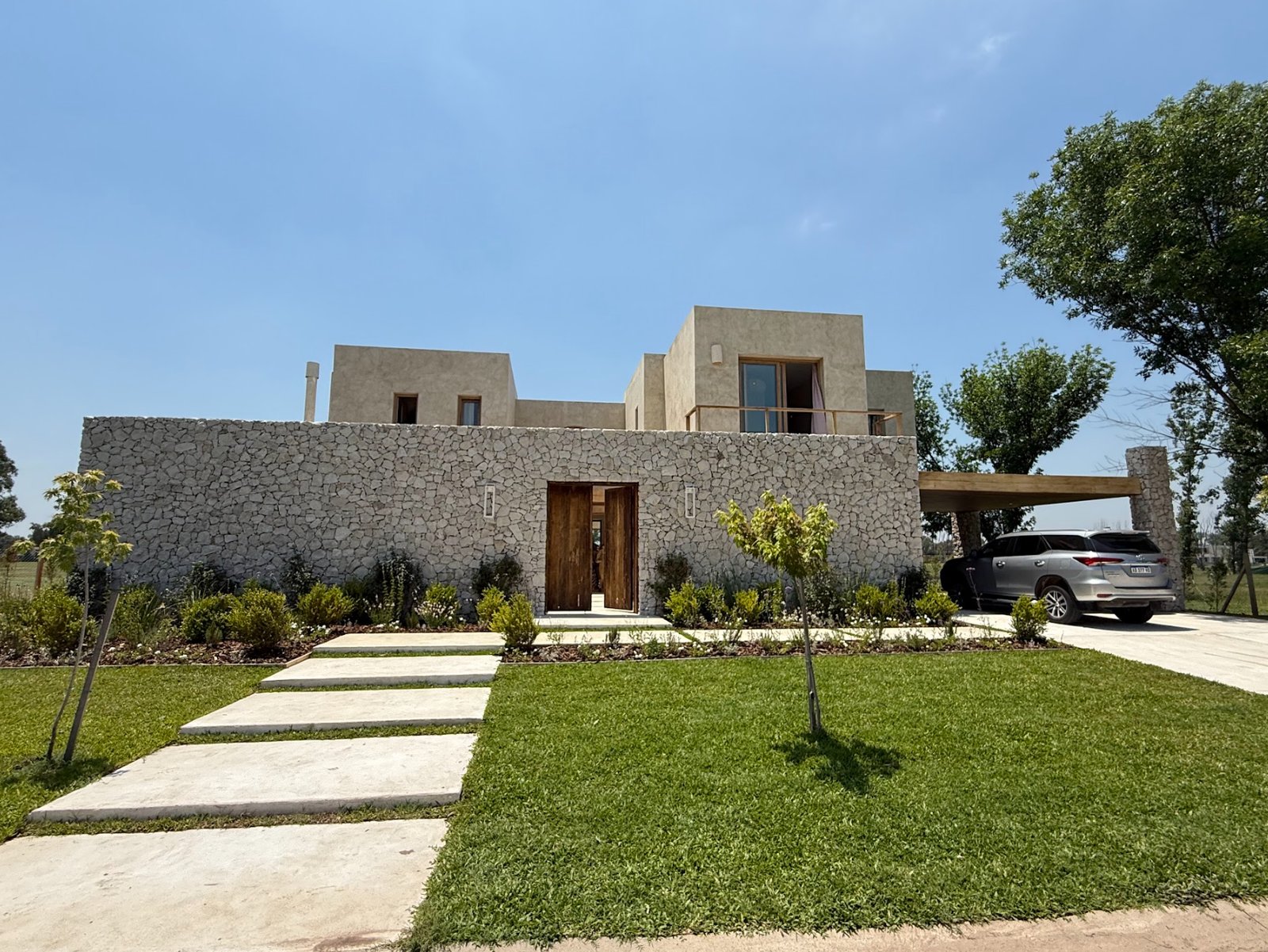 Fachada moderna con piedra, madera y jardines verticales — proyecto La Verbena, por Grupo Pauta Arquitectura, en Alejandro Korn 3150