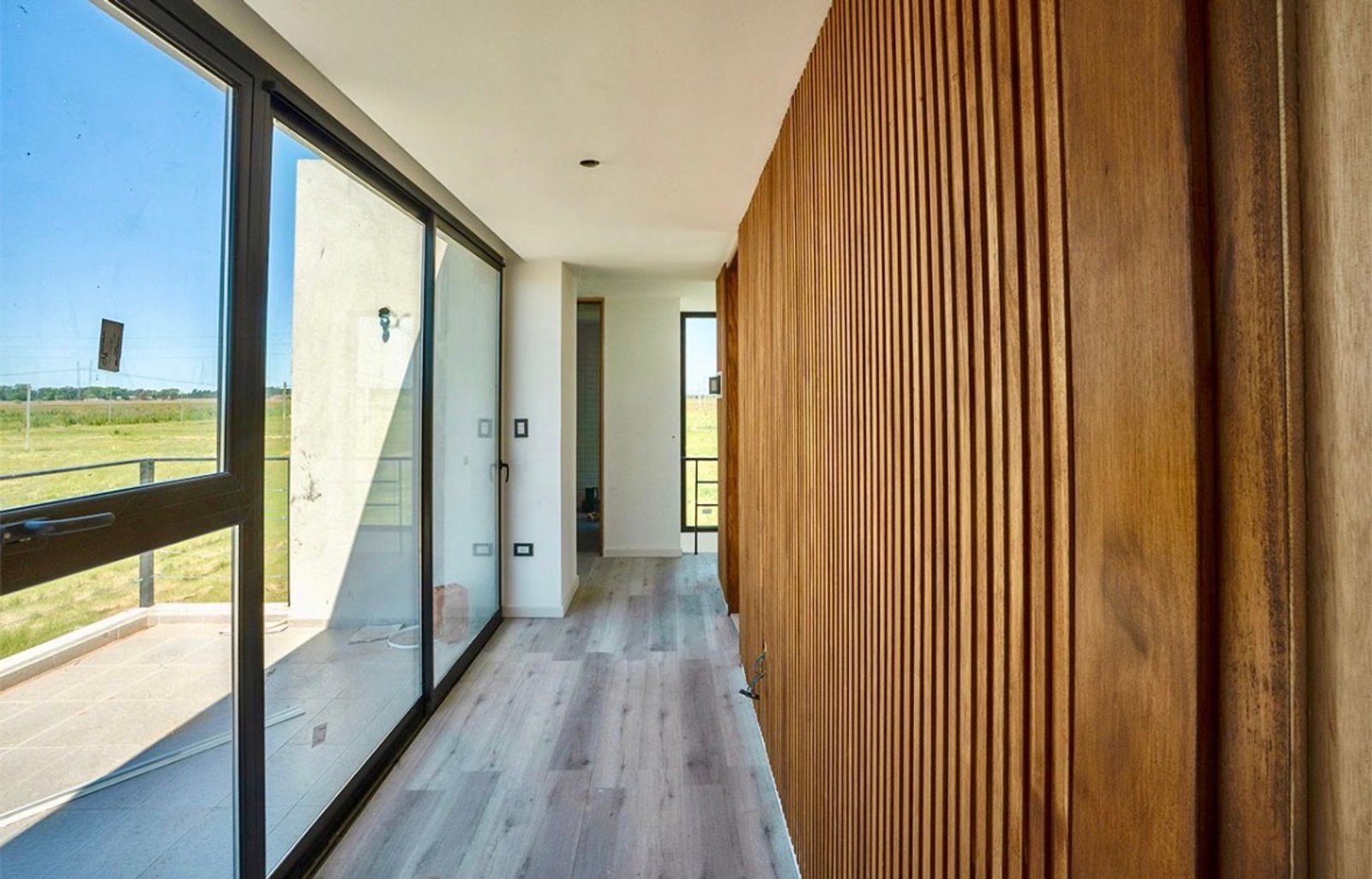 corredor moderno com parede de ripas de madeira e janelas — projeto Proyecto Casa Doble, La Plata, por Estudio cardo, em RP2 2