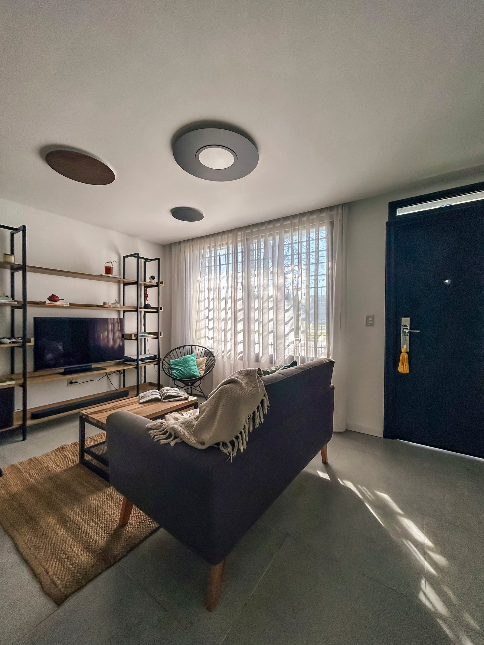 Sala moderna escandinava com sofá cinza, tapete de fibras naturais e luz abundante — projeto Vivienda Mari y Lean, por Jeitinho Estudió Creativo, em La Plata