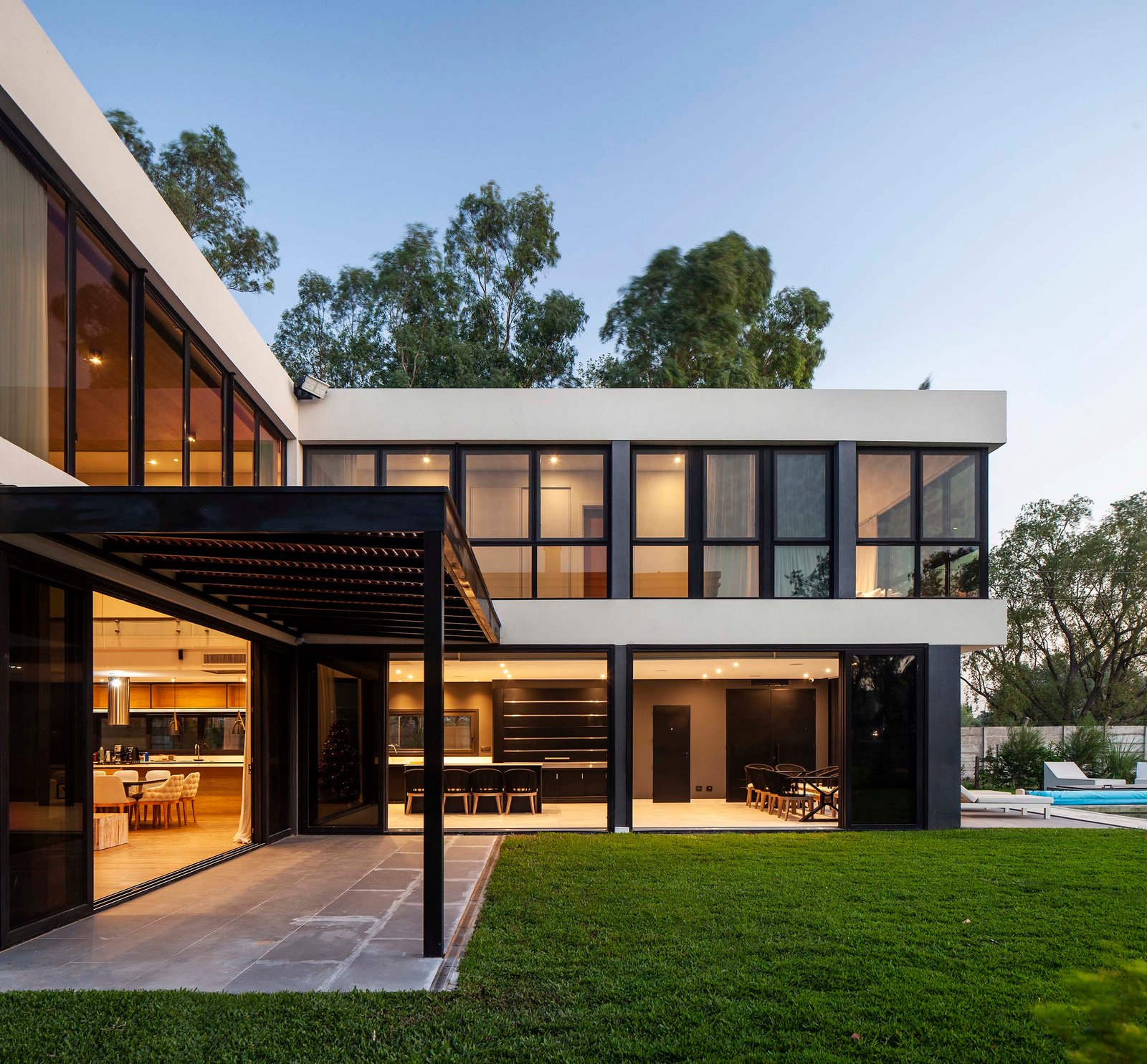 fachada moderna con amplios ventanales y área exterior — proyecto CASA T199, por A'PRIMA - Arquitectura Sustentable, en Los Robles 5901