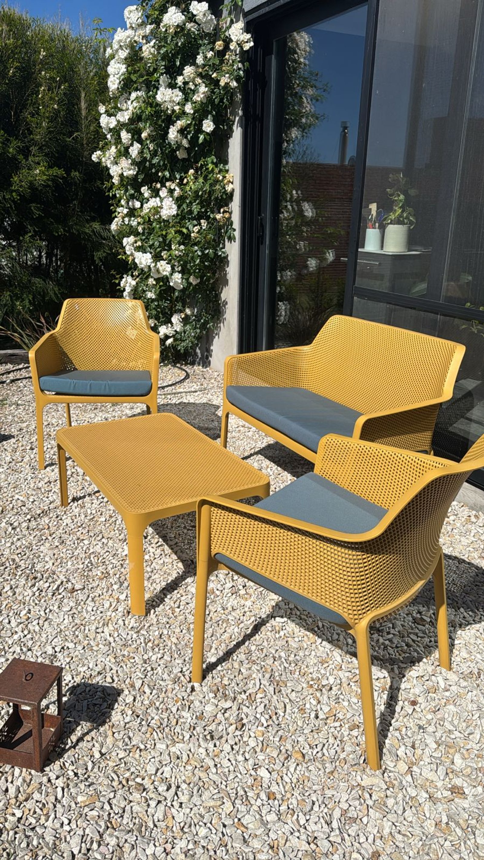 Patio moderno con sillones y mesa de plástico tejido color ocre — proyecto Living Exterior, por Casa Nuñez
