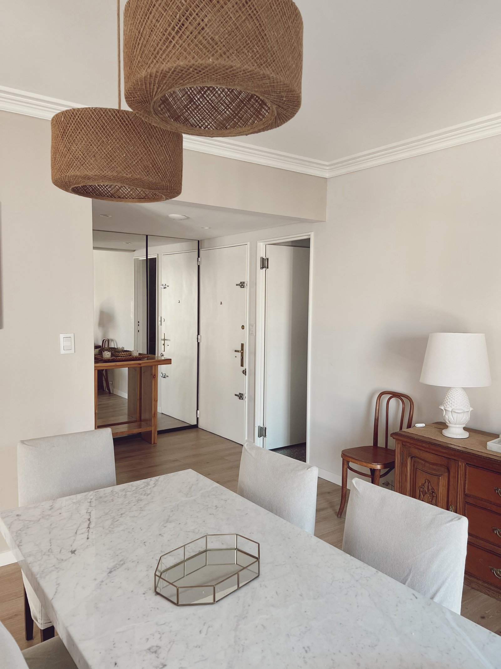 Comedor moderno con mesa de mármol y sillas blancas, lámparas de mimbre — proyecto Juncal, por Equipe, en Buenos Aires