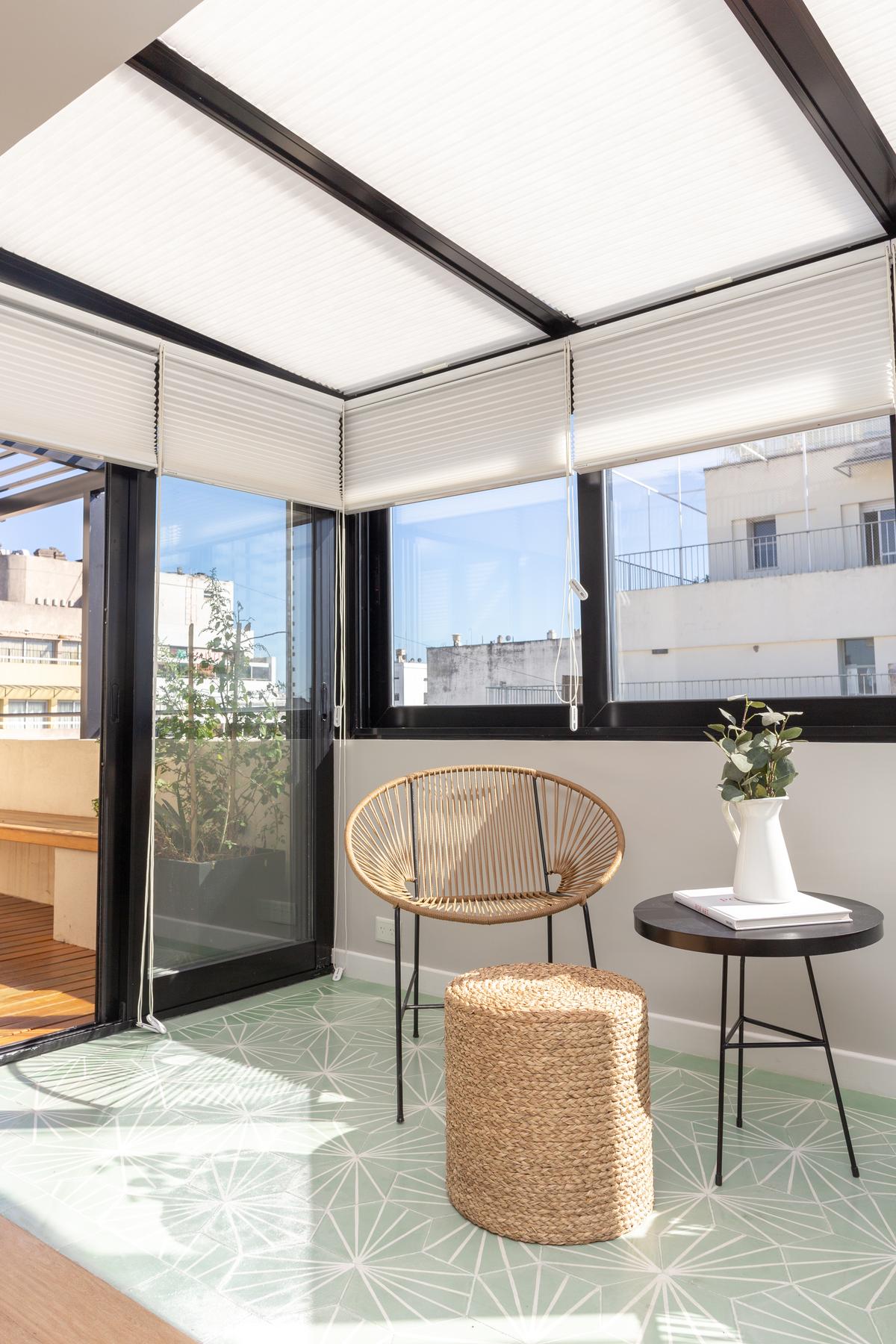 Varanda com cadeira de rattan e piso geométrico — projeto Viamonte II, por WA arquitectura, em CABA