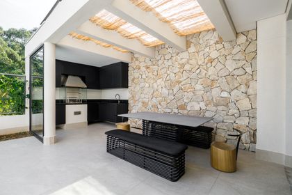 Cocina exterior moderna con pared de piedra y pérgola de madera — proyecto CASA DANIELA ALPHA, por Yannick Athia, en São Paulo