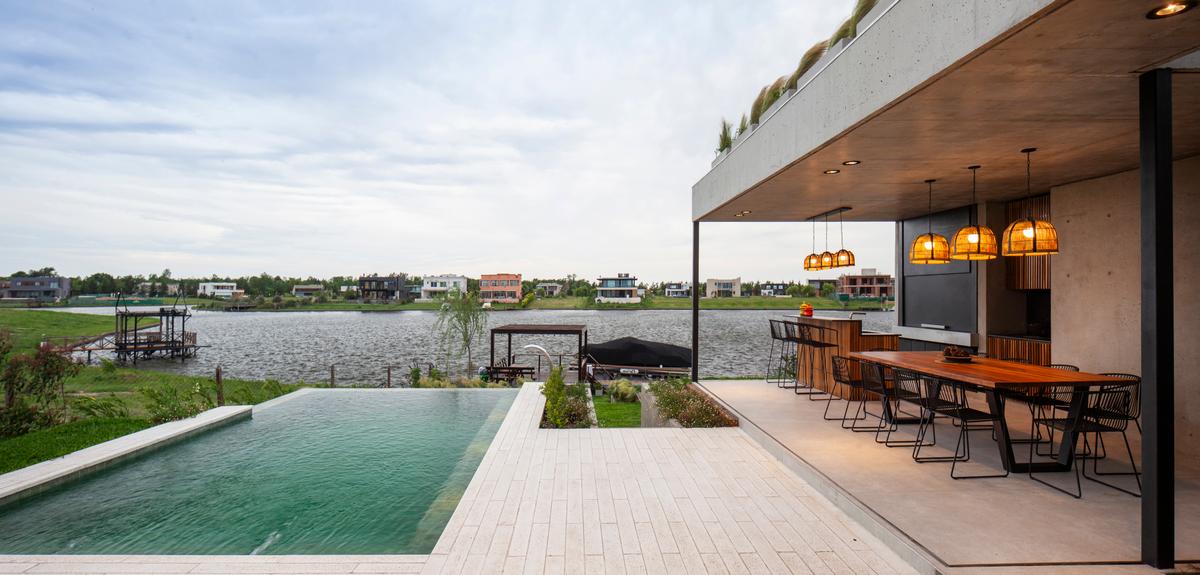 Piscina infinita e sala de jantar externa moderna com vista para o lago — projeto Casa Boating, por LSA., em Belén de Escobar