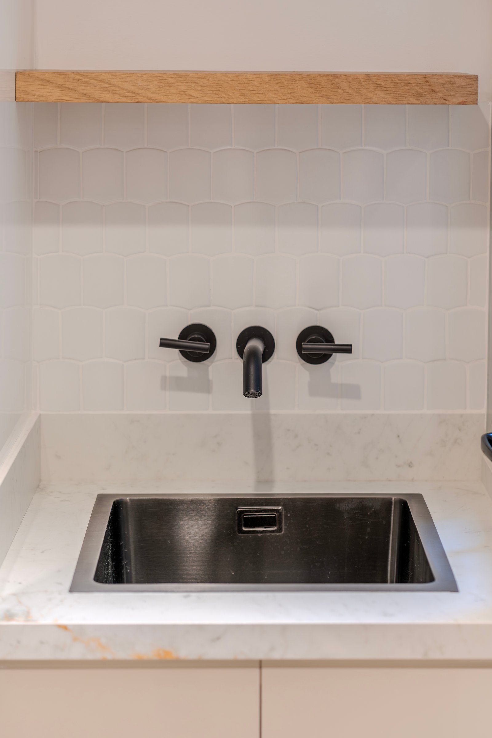 Baño moderno con grifería negra, azulejos geométricos y repisa de madera — proyecto Senillosa - Cocina / Lavadero / Mudroom, por Blue Rabbit Design, en Caballito