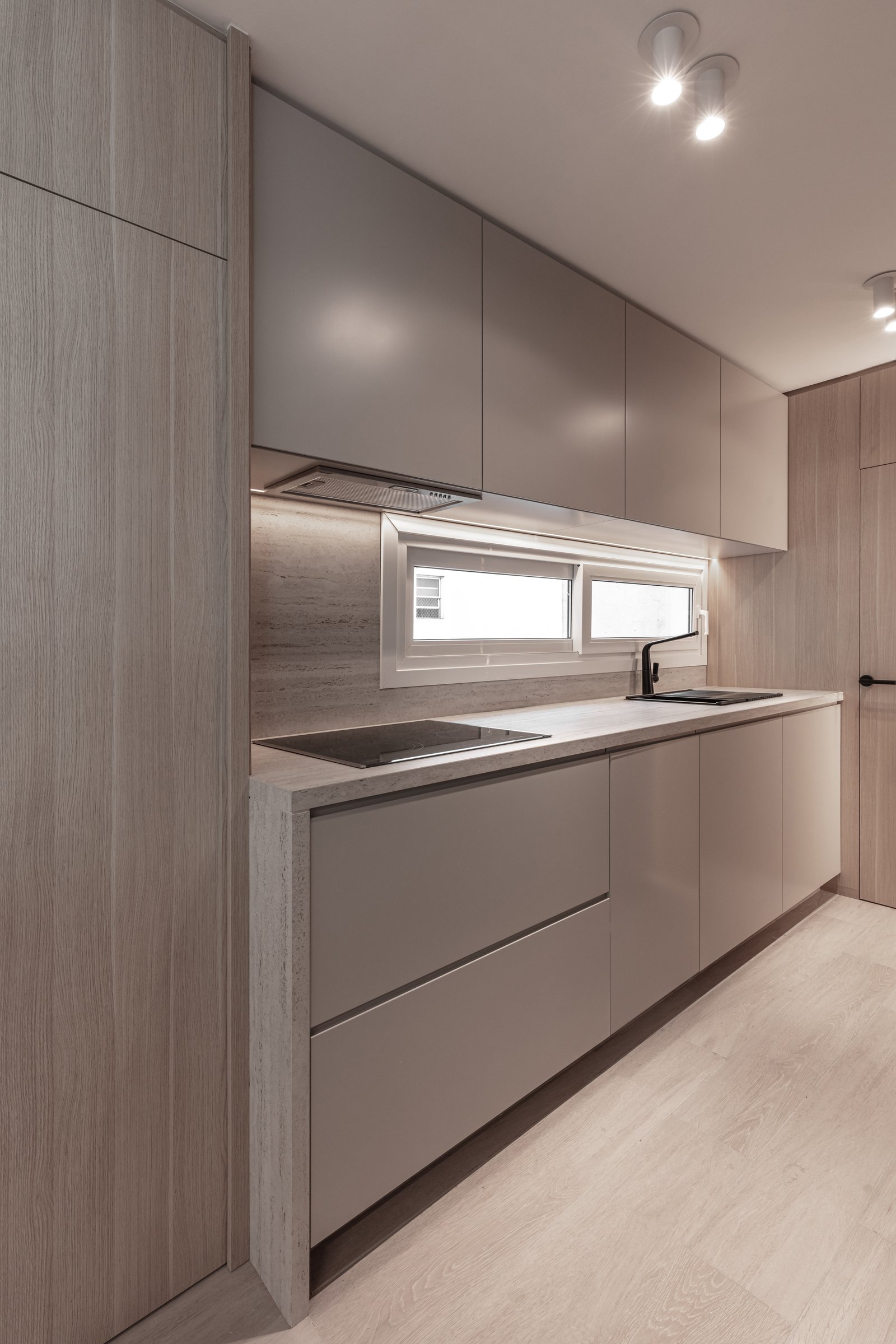 Cozinha moderna minimalista com armários de madeira e cinza, janela longa e luz indireta — projeto Eslovenia | Pied-à-terre | Lucia Quinteros, por Ren Studio, em Cdad. Autónoma de 
