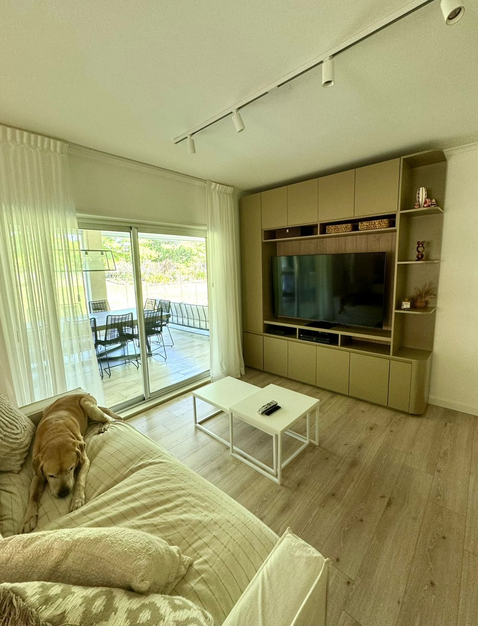 Living moderno con sofá grande, ventanales y unidad de TV empotrada — proyecto La rinconada, por Casa Fi, en Pilar