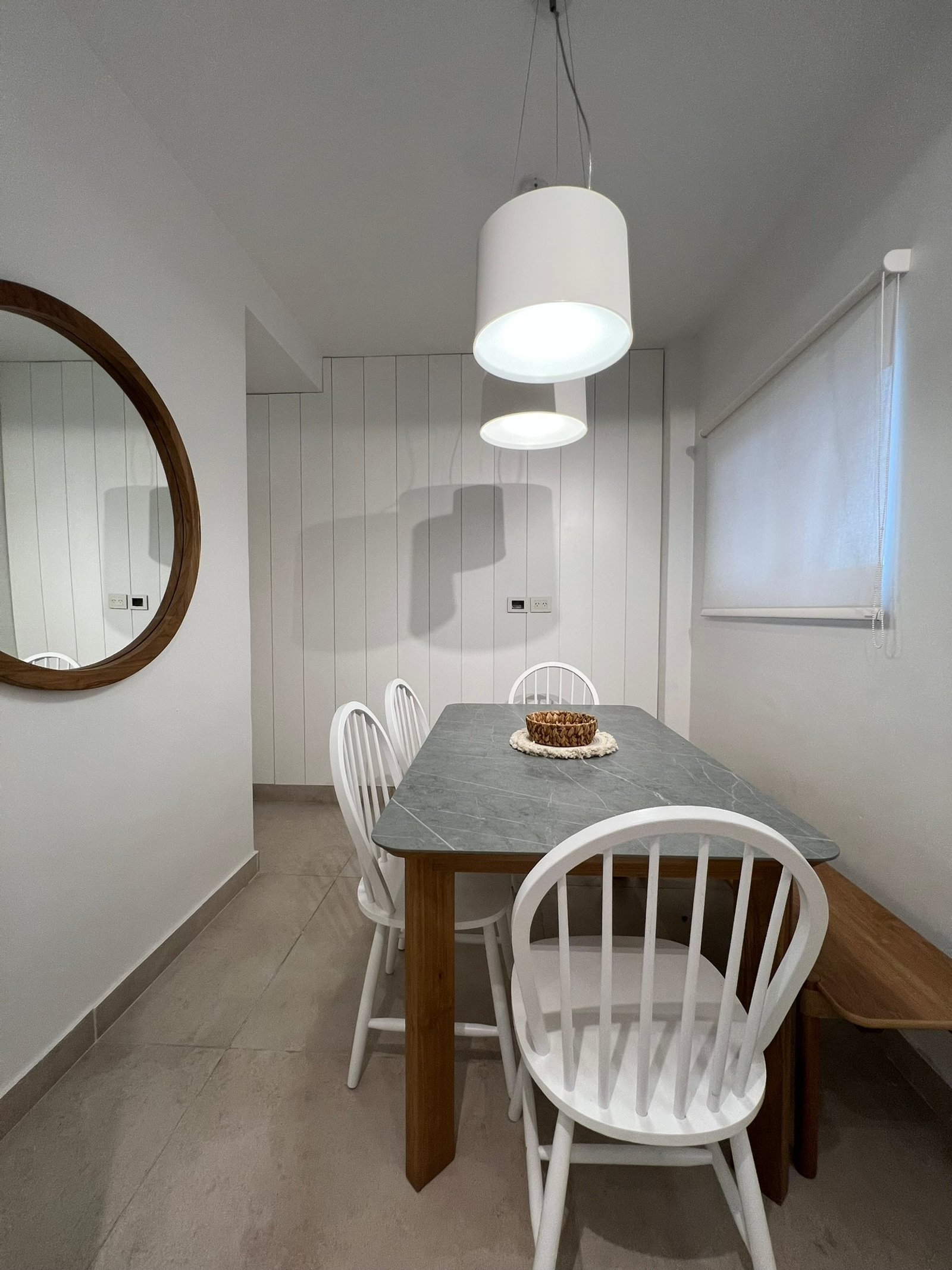 Comedor moderno con mesa de piedra oscura y sillas blancas de madera — proyecto Perón , por MDBK Arquitectura, en Barrio Norte