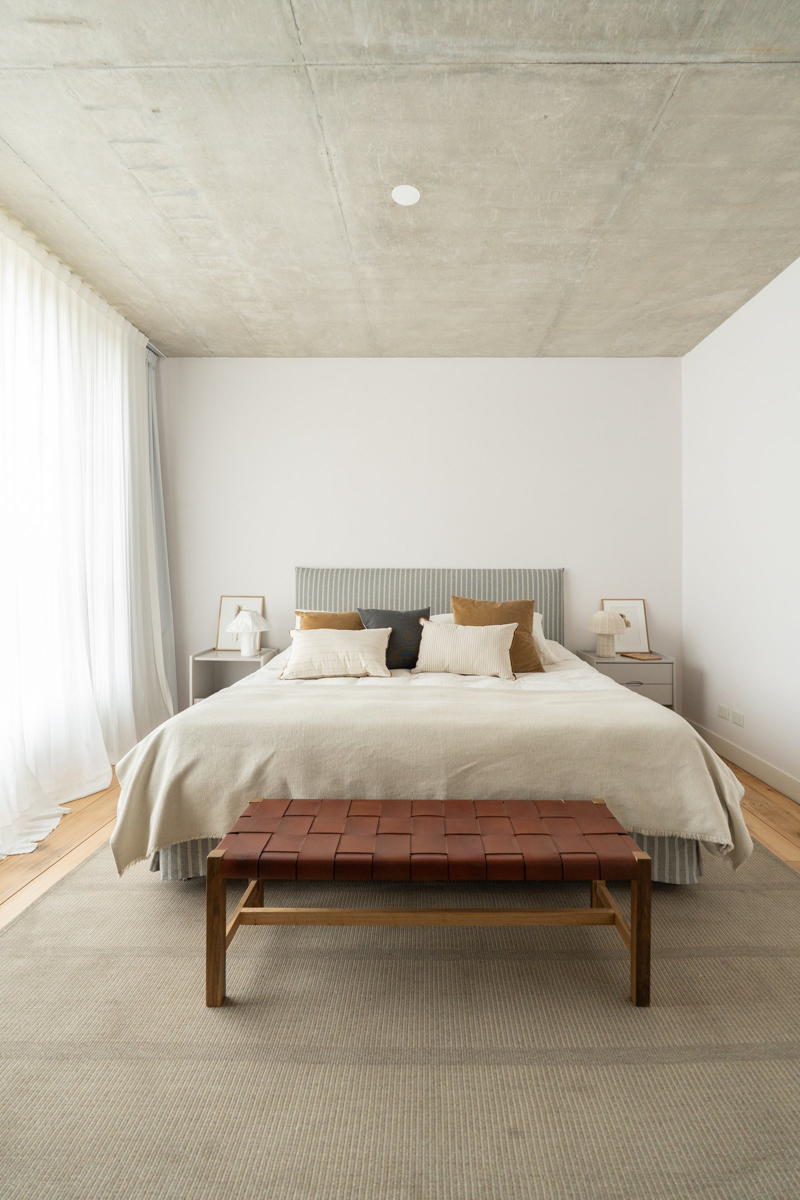 Dormitorio moderno con techo de hormigón expuesto y banco de cuero tejido — proyecto Carpinchos, por LACROZE DESIGN STUDIO, en Nordelta