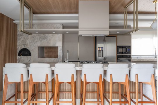 Cocina moderna blanca y mármol con isla y banquetas — proyecto Cozinha e área gourmet reformados, por BRUNA CALDAT ARQUITETURA, en Curitiba
