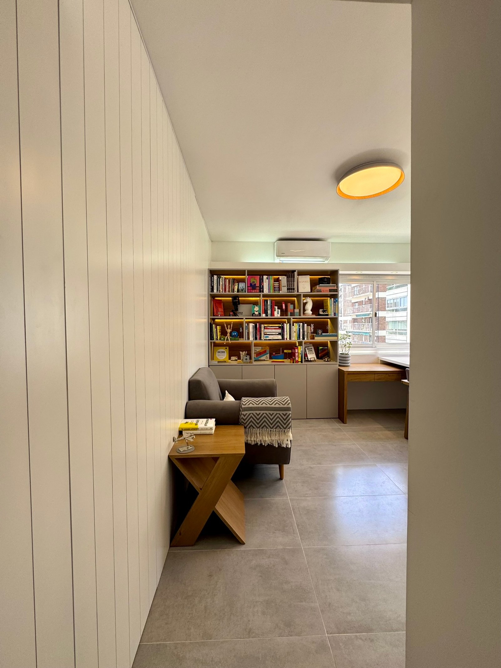 Sala de estar moderna com painéis de madeira branca e estante embutida — projeto Matienzo, por MDBK Arquitectura, em Belgrano