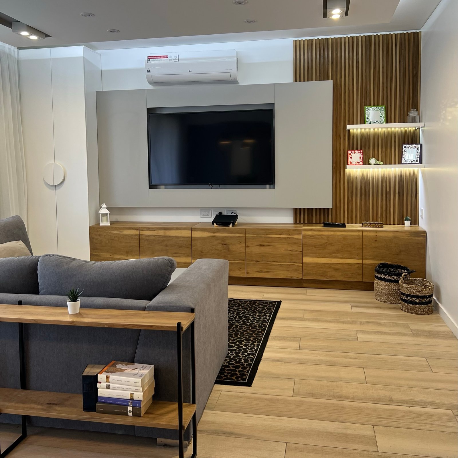 Living moderno con pared de listones de madera y TV grande — proyecto Diaz Velez II, por MDBK Arquitectura, en Almagro