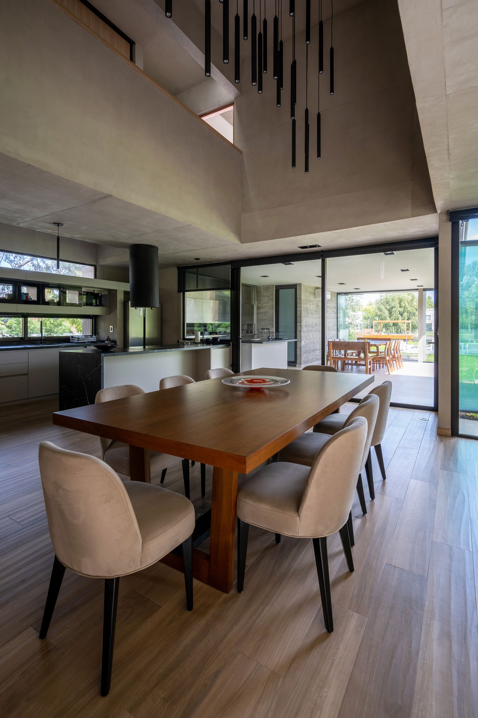 Comedor moderno con cocina integrada y ventanales amplios — proyecto Casa Miralagos II, por Besonías Almeida arquitectos, en La Plata