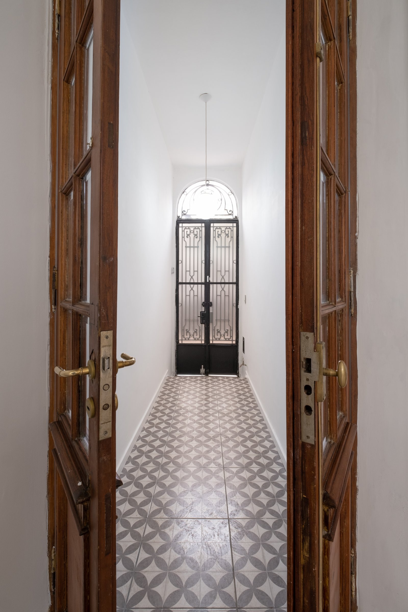 Pasillo interior con puertas de madera y rejas ornamentales — proyecto Casa Patio, por Herrera Ungaro, en San Cristóbal