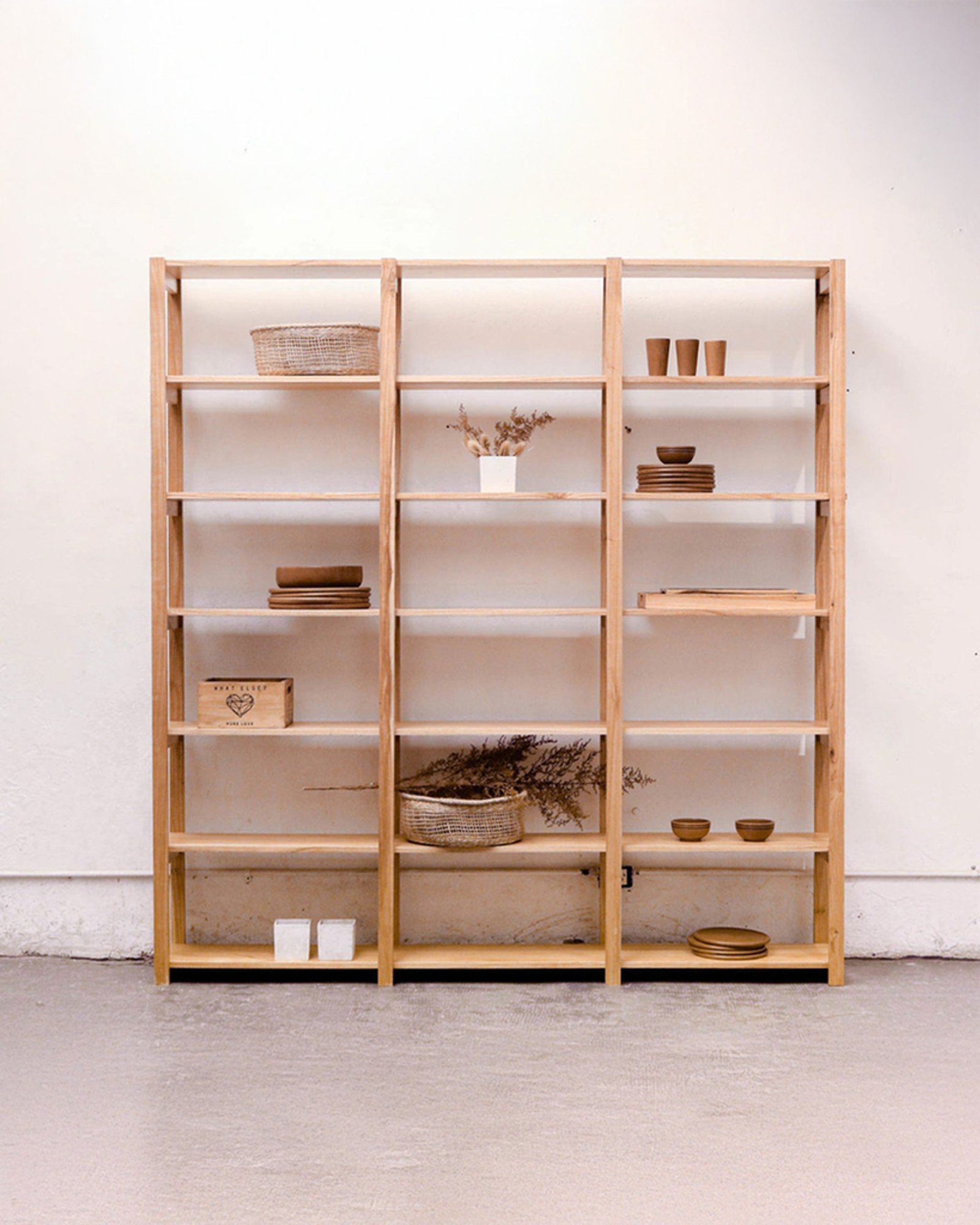 Estante de madeira clara com objetos decorativos minimalistas — projeto Living, por BLVD Furniture
