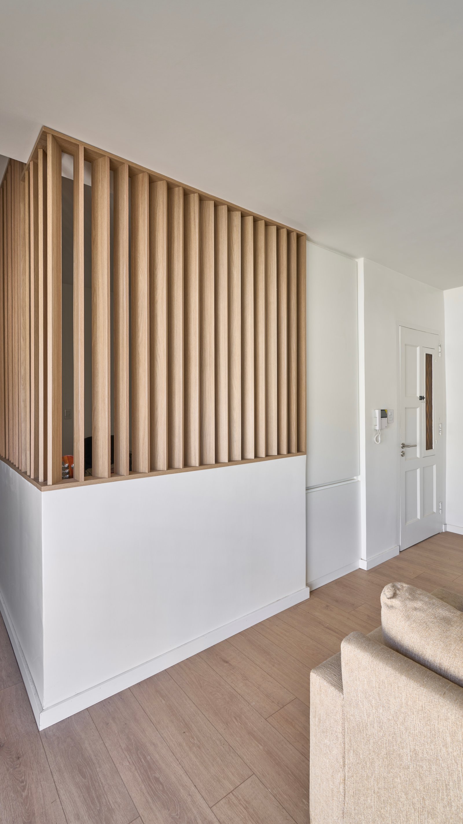 Espacio minimalista con divisor de madera y sofá crema — proyecto Granville, por Baler.Gelbert Arquitectura, en B1845 José Marmol