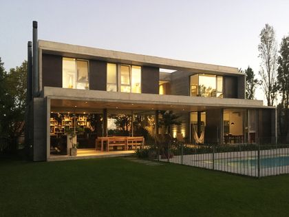 Casa contemporánea de dos plantas con fachada gris y vidrio, atardecer — proyecto Casa en Santa Barbara, por Crea Constructora, en Benavidez