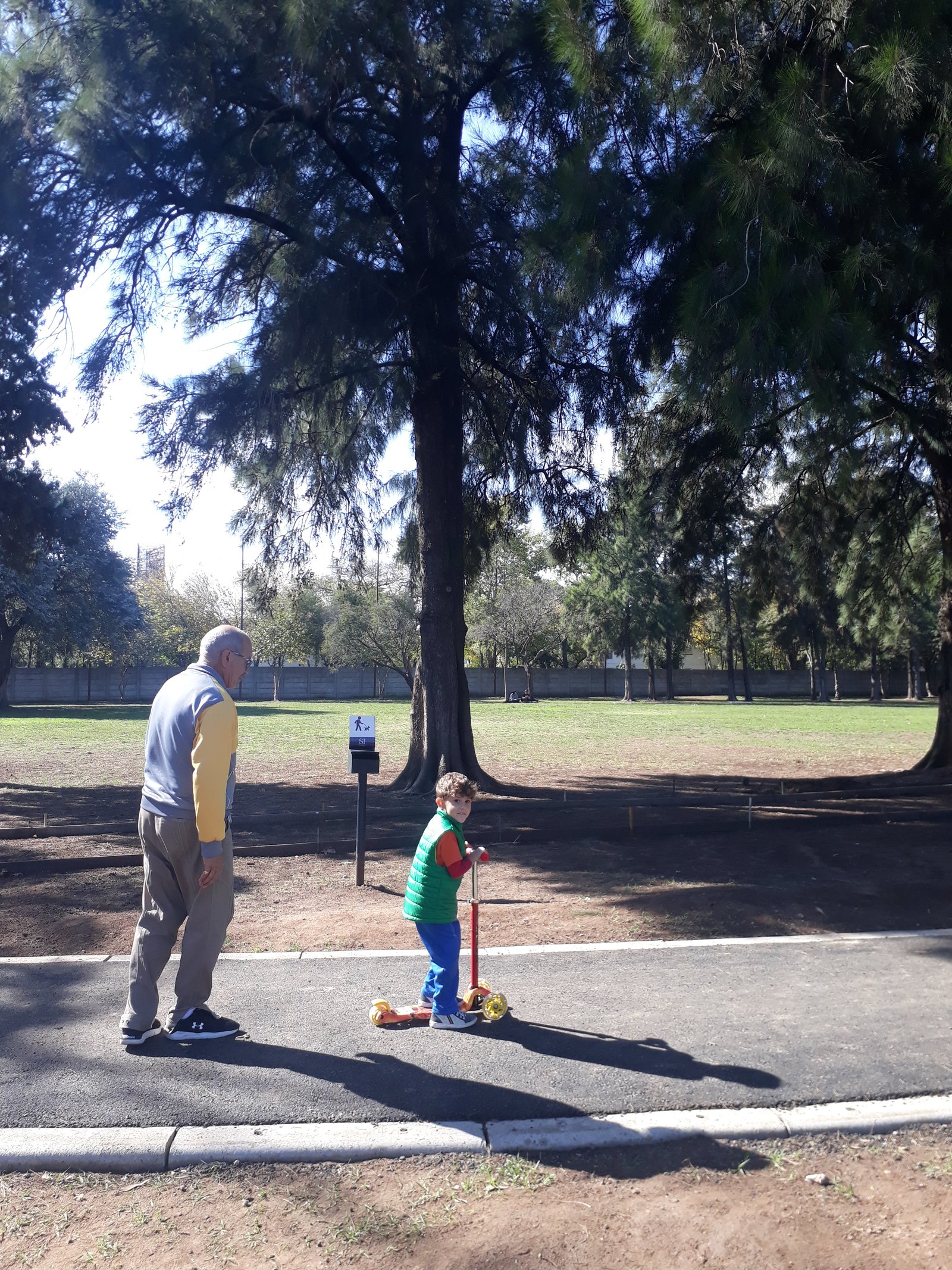 Hombre y niño en patinete en un parque — proyecto Parque Público Villa Adelina, por Estudio Rifahi, en B1607 Villa Adelina